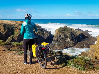Cyclist enjoys the view at the cliffs in Sines