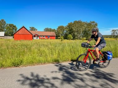 Radfahrer auf dem Kattegattleden bei Hjortsberg – mit typischem rotem Schwedenhaus im Hintergrund
