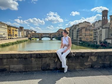 Frau sitz auf Brücke und blickt auf die berühmte Ponte Vecchio