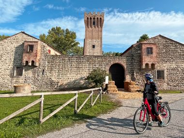Radfahrerin vor der imposanten Burg Sankt Martin della Vaneza