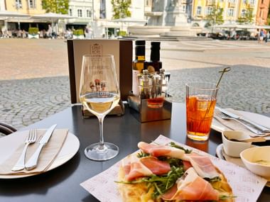 Hiking stop at Piazza Walther in Bolzano with an aperitif and a foccacia topped with air-dried ham and rocket salad