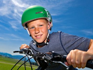 Child with green helmet on bicycle in the Salzburg Lake District