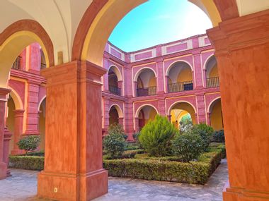 Green inner courtyard surrounded by colourful Spanish-style monastery walls