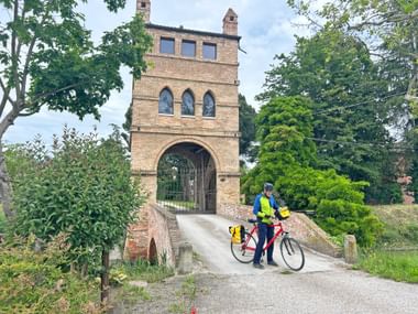 Cyclist in front of a stone arch near Madonna della Rosario