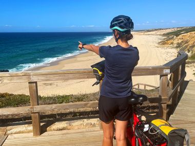 Cyclist on wooden walkway with beach and sea in the background