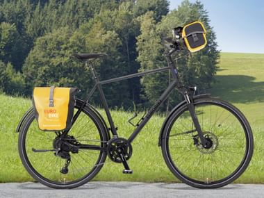 Rental bike-PLUS, parked on roadside with green meadow and forest in background.