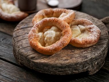 Auszogne mit Staubzucker auf einem Holzbrett