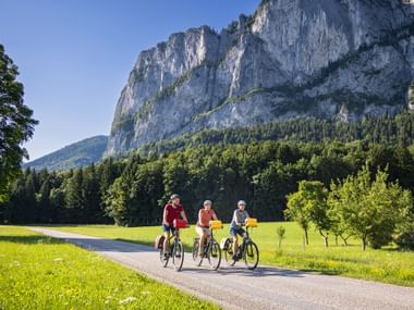 Drei Radfahrer radeln am Mondsee an der Drachenwand vorbei