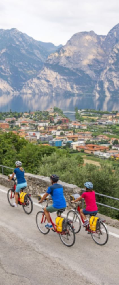 Eine Radfahrgruppe auf einem Radweg oberhalb von Torbole mit Blick auf den Gardasee