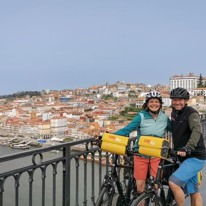 Happy couple cycling on the bridge in Porto