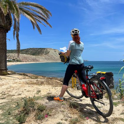 Radfahrerin beim Lesen des Routenbuchen am Praia de Luz