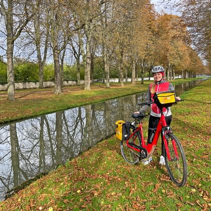 Cyclist in autumnal avenue on a small river