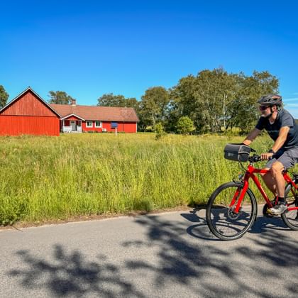 Radfahrer auf dem Kattegattleden bei Hjortsberg – mit typischem rotem Schwedenhaus im Hintergrund