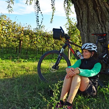 Eine Radfahrerin lehnt an einem Baum inmitten der Weinberge nahe Borgo Lorenzoni
