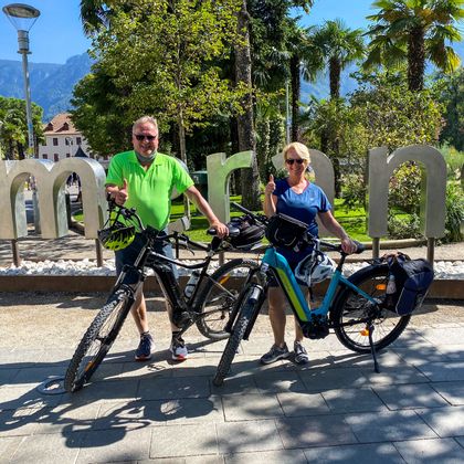 Two cyclists in front of merano lettering