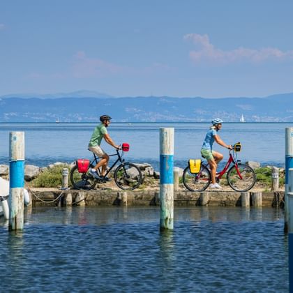 Two cyclists ride along the harbour in Grado