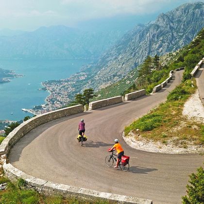 Two cyclists on a cycle path over serpentines into the Bay of Kotor