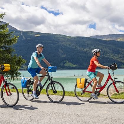 Cyclists at the sunken church tower on Lake Reschen