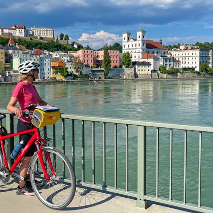 Cyclist during a stopover on a bridge with a view of Passau