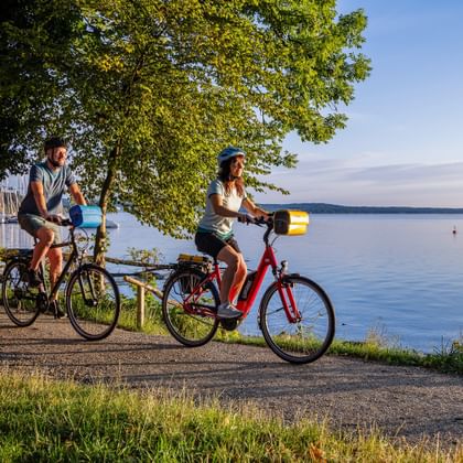 Three cyclists near the harbour, in the evening atmosphere on Lake Starnberg
