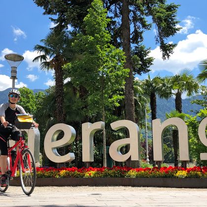 Cyclist in front of the Merano lettering