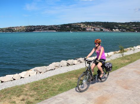 Radfahrerin am Küstenradweg mit Ausblick auf das Meer
