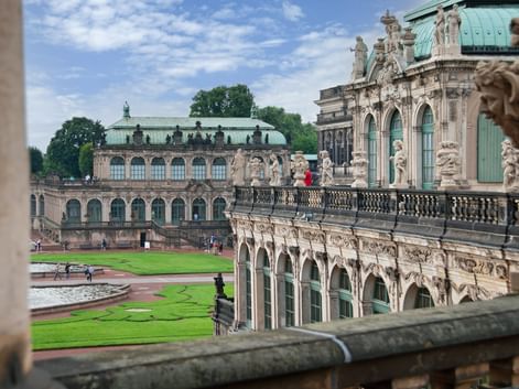 Blick auf den barocken Innenhof des Dresdner Zwingers mit verzierten Sandsteingebäuden, grünen Kupferdächern, Skulpturen und Rasen.
