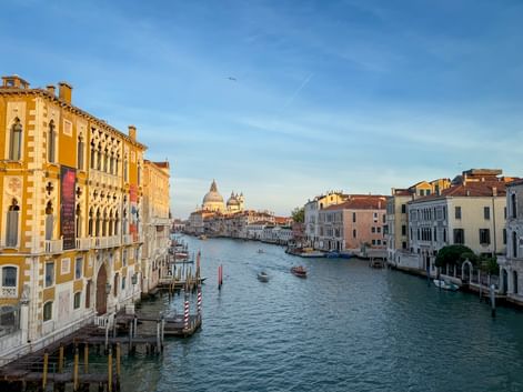 Blick entlang des Canal Grande in Venedig mit historischen Palästen zu beiden Seiten und der weißen Kuppel der Kirche Santa Maria della Salute.
