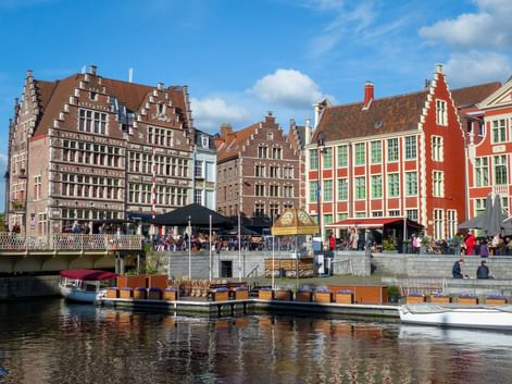 Bunte flämische Giebelhäuser entlang des Graslei-Kanals in Gent mit Booten am Ufer und Menschen auf dem Kai.