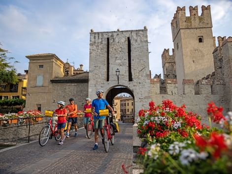 Cyclists push their bikes through the archway of the castle in Sirmione