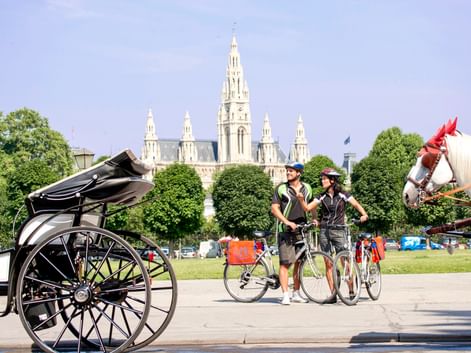 Radler vor Wiener Rathaus und Blick auf Fiaker
