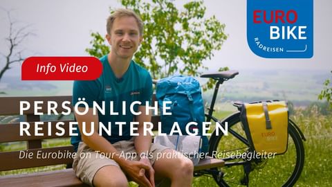 Lächelnder Radfahrer in türkisem Eurobike-Shirt auf Bank sitzend mit Fahrrad und gelben Taschen. Texteinblendung: Persönliche Reiseunterlagen.