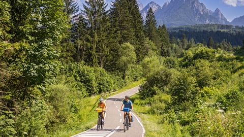 Zwei Radfahrer auf dem Radweg im Kanaltal bei Tarvis mit den Bergen im Hintergrund