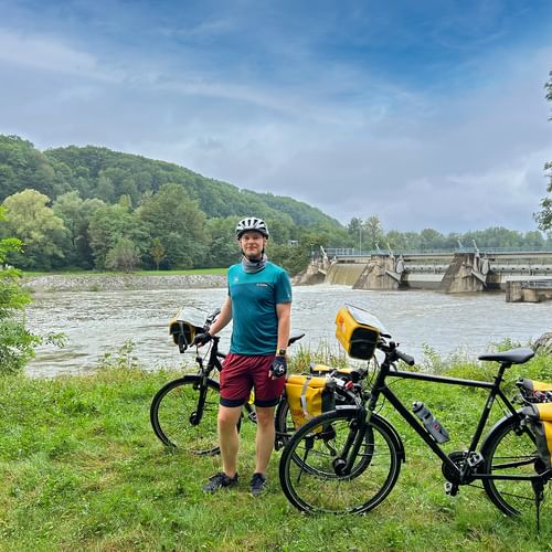 Cyclist with two bikes and dam in the background