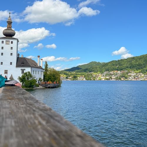 Radfahrerin blickt auf Schloss Ort am Traunsee