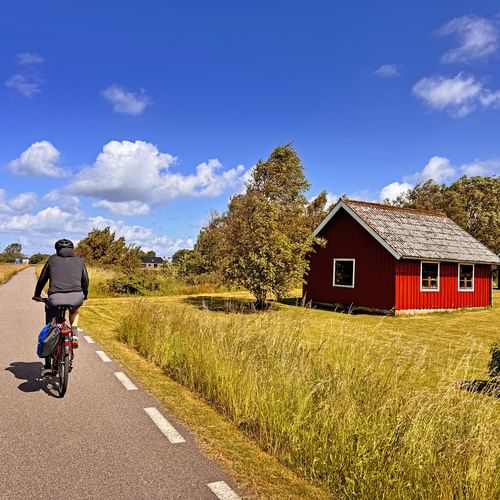 Radfahrer in Falkenberg, der an einem roten Haus vorbeifährt