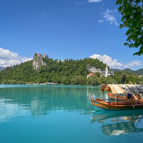 Bleder See mit Boot und Burg im Hintergrund