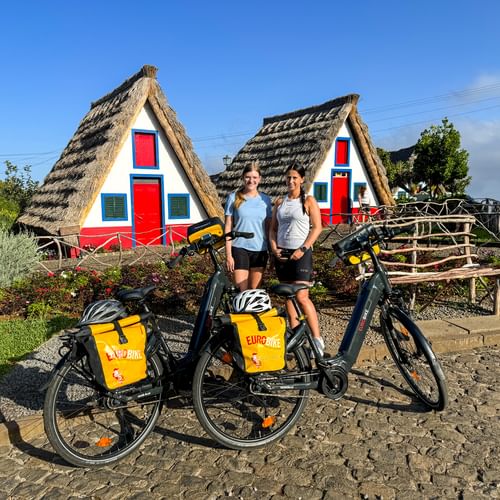 Two cyclists in front of the famous straw houses in Santana