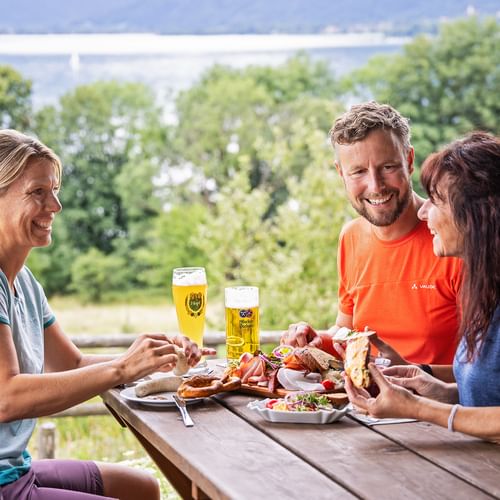 Drei Personen machen Brotzeit am Tegernsee in Kaltenbrunn