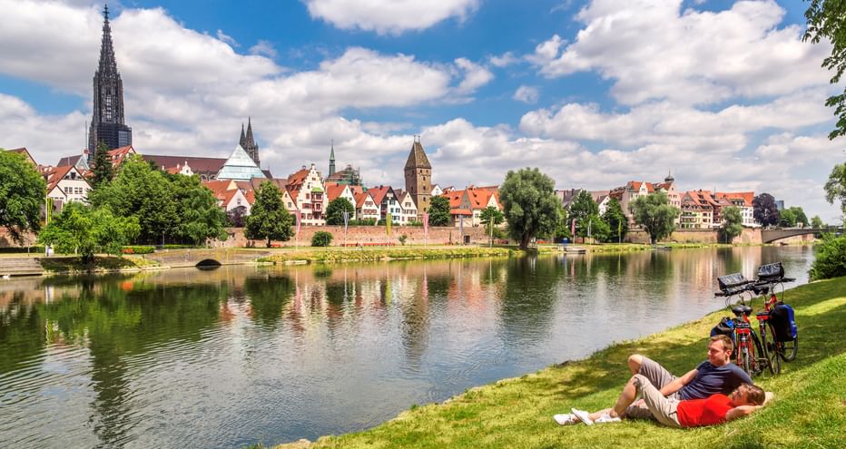 Cycling break by the river with a view of Ulm's old town and cathedral