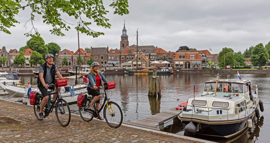 Zwei Radfahrer fahren entlang des Hafens von Weerribben-Wieden