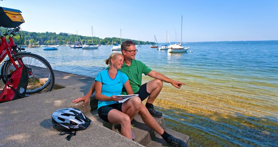 Cycling break of a couple on the shore of the Ammersee at the harbour of Herrsching