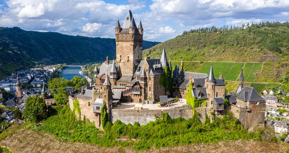 View of the Reichsburg Cochem, surrounded by vineyards and the town, with the Moselle in the background