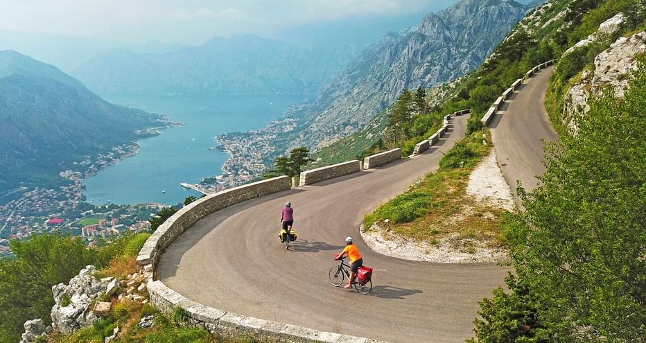 Two cyclists on a cycle path over serpentines into the Bay of Kotor