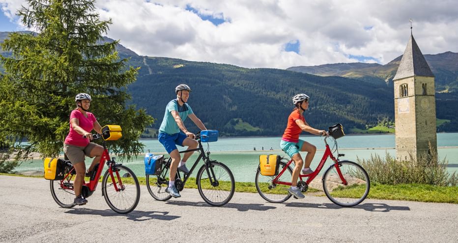 Cyclists at the sunken church tower on Lake Reschen