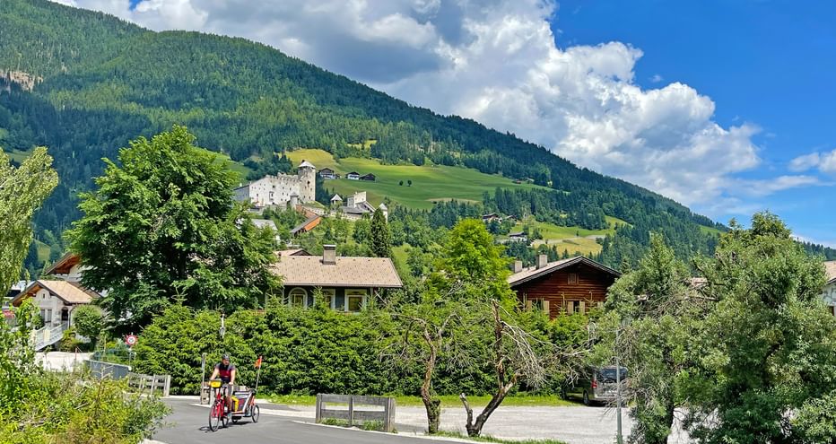 Radfahrer mit Kinderanhänger in Sillian, im Hintergrund Burg Heinfels