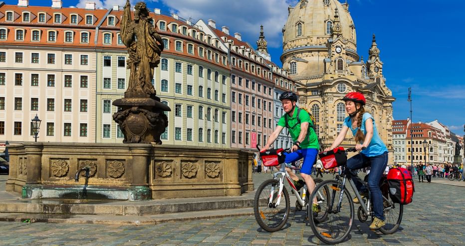 Zwei Radfahrer neben einem Brunnen auf dem Vorplatz der Frauenkirche in Dresden