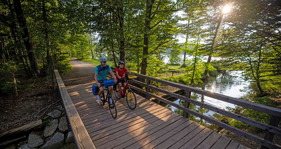 Zwei Radfahrer auf einer Brücke im Wald am Ostersee