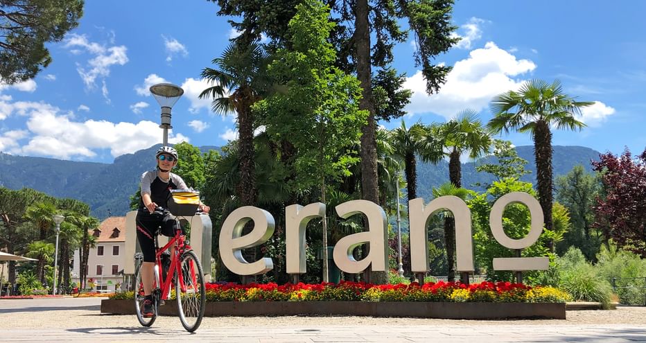 Cyclist in front of the Merano lettering