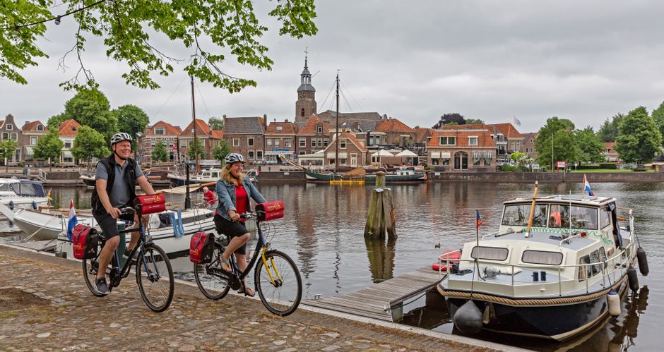 Two cyclists ride along the harbour of Weerribben-Wieden